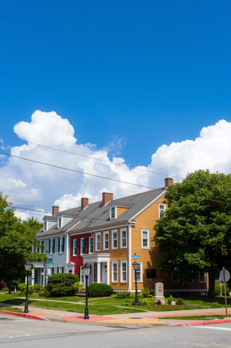 Colorful historic New England clapboard houses in blue, red, and yellow along a sunny small-town street