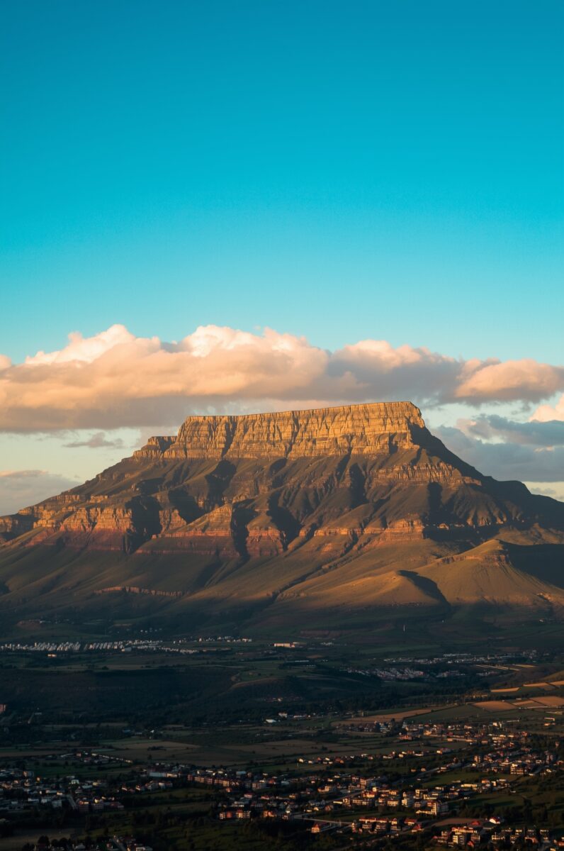 Table Mountain Cape Town South Africa at golden hour sunset with flat summit clouds and city below