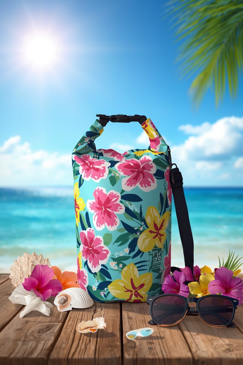 Colorful tropical floral dry bag with sunglasses and seashells on wooden deck overlooking turquoise ocean