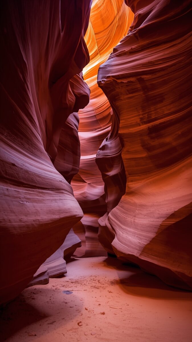 Narrow sandstone slot canyon with swirling orange and red rock walls illuminated by natural light from above