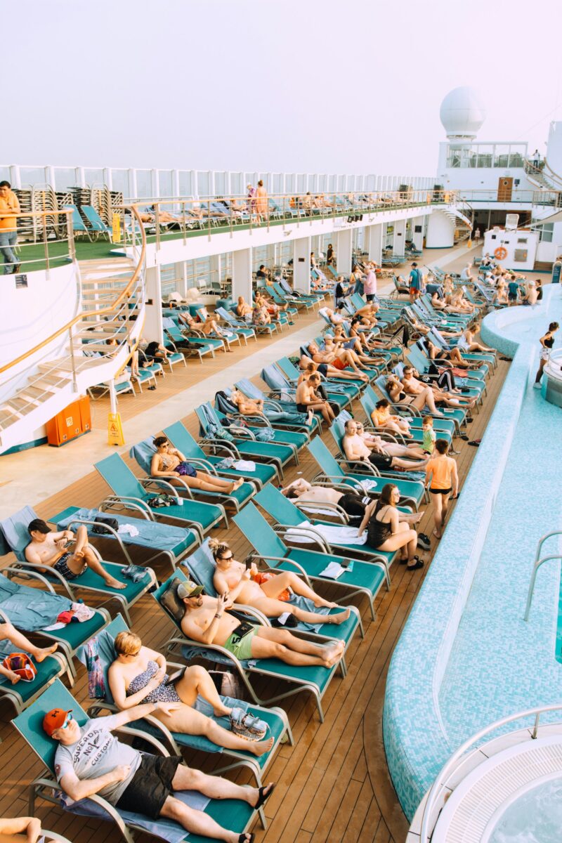 Rows of sun loungers packed with people beside a cruise ship's pool on a sea day