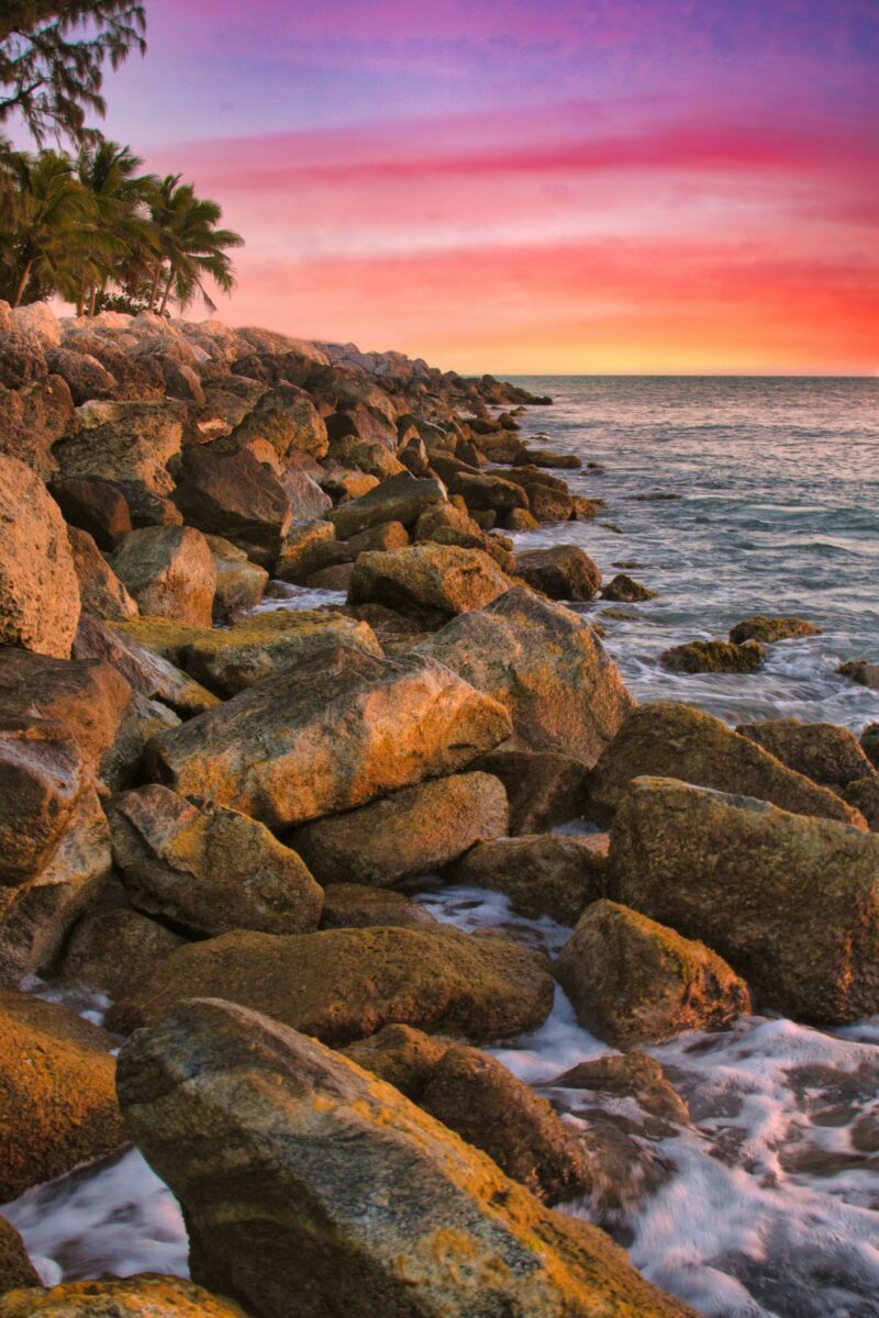Large rocks along the shore in Key West at sunset, with a small strip of beach