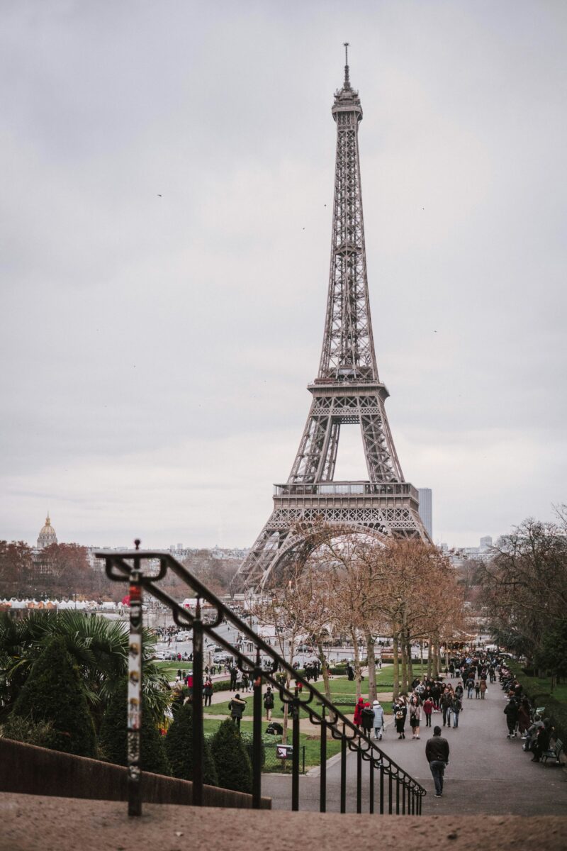 Crowds walking through the Trocadero gardens toward the Eiffel Tower on a gray winter day