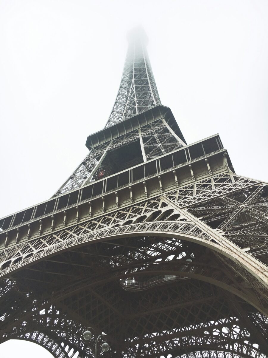 Looking straight up at the Eiffel Tower from underneath, its top lost in white mist