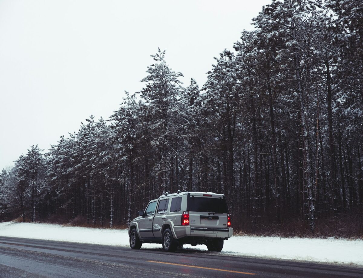 A silver SUV parked on the shoulder of a plowed road beside snow-dusted pines near Wisconsin Dells