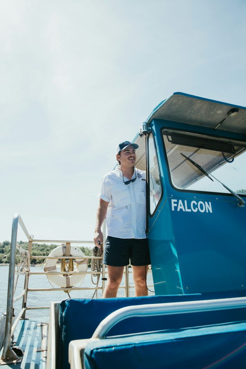 A tour boat captain at the helm of the blue boat Falcon on the river at Wisconsin Dells in summer