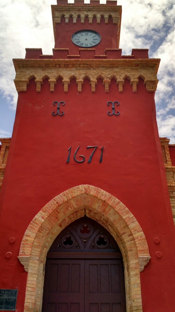 The red clock tower of Fort Christian in Charlotte Amalie, St. Thomas, with 1671 over a pointed brick arch