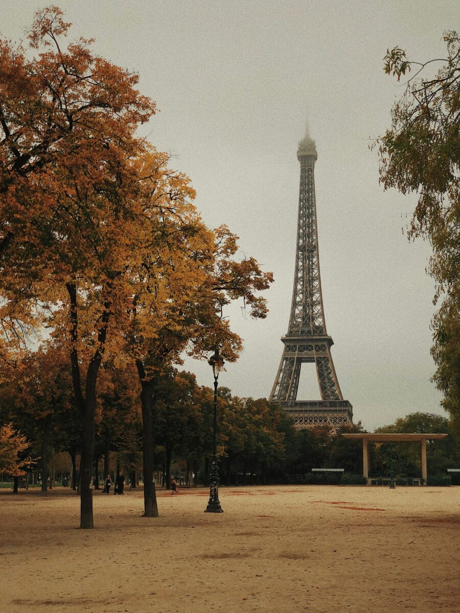 The Eiffel Tower with its top in low cloud, seen past autumn trees on the Champ de Mars